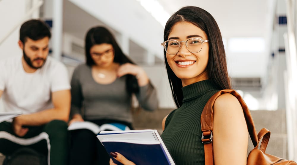 An older woman and a young girl with a stuffed bear smile and wave at a laptop.